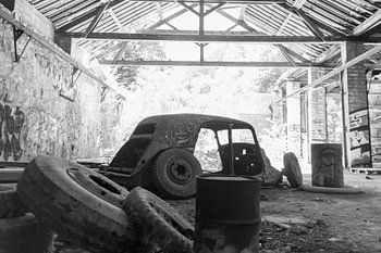 Zwart-witfoto van een auto in verlaten fabriek