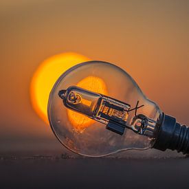Light bulb on the beach in front of the setting sun. by Smit in Beeld