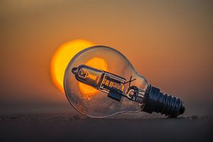 Gloeilampje op het strand voor de ondergaande zon.