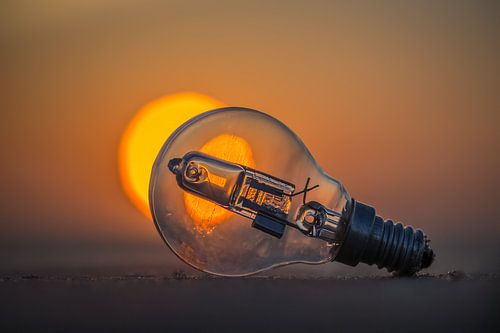 Gloeilampje op het strand voor de ondergaande zon. van Smit in Beeld