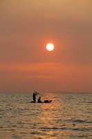 Father and son, at sunset, paddling at sea (standing)