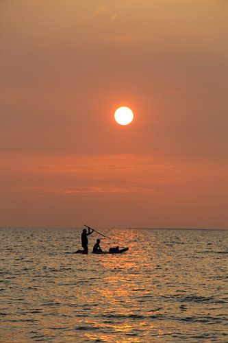 Vater und Sohn, bei Sonnenuntergang, paddelnd auf dem Meer (stehend)