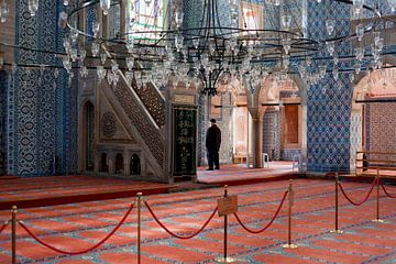 Homme en prière, Mosquée à Istanbul, Turquie, avec de beaux carreaux bleus et un tapis rouge.