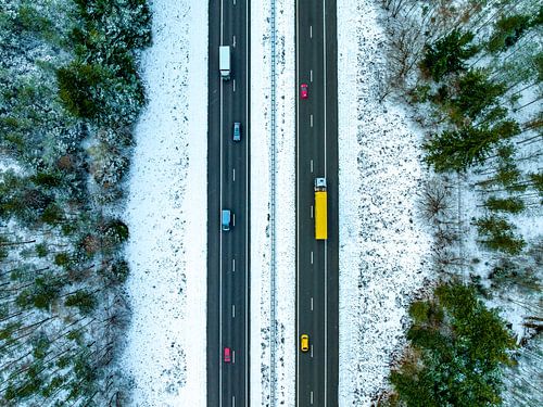 Snelweg door een besneeuwd boslandschap van bovenaf gezien