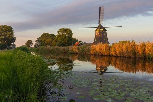 Molen tijdens zonsondergang, met reflectie in het water