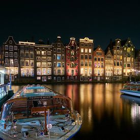 Het Damrak met rondvaartboten te Amsterdam in de avond van Ad Jekel