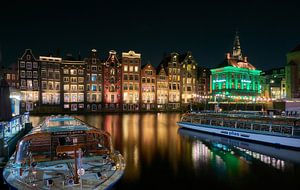Le Damrak avec les bateaux de canal à Amsterdam le soir