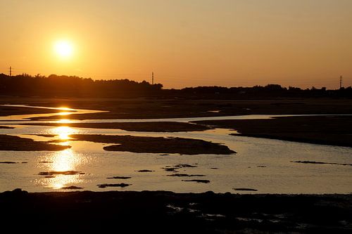 ondergaande zon over een meandert wad Bretagne