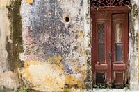 Dark red old dilapidated door next to old wall