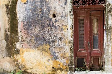 Vieille porte rouge foncé délabrée à côté d'un vieux mur sur Yke de Vos