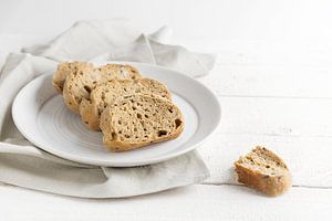 vers volkorenbrood op een bord, op een wit geschilderde rustieke houten tafel, kopieerruimte, gesele