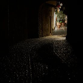 View through a tunnel to a dimly lit alleyway in the old town centre of Malcesine