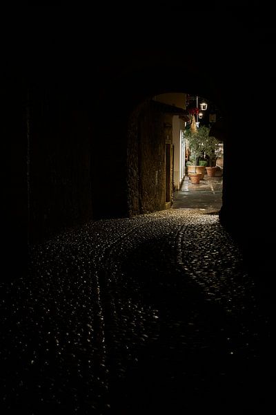 Blick durch einen Tunnel zu einer schwach beleuchteten Gasse in der Altstadt von Malcesine von Heiko Kueverling