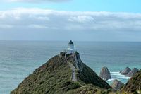 Une côte accidentée avec des pierres et un phare