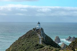 Rough coast with stones and a lighthouse by Marco Leeggangers