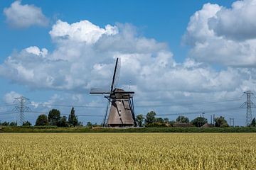 Landschap met prachtige traditionele Nederlandse windmolen met blauwe lucht en wolken.