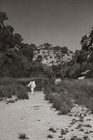 Woman walks on beach in front of rocks in Majorca
