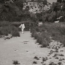 Une femme marche sur la plage devant des rochers à Majorque sur Photo Atelier