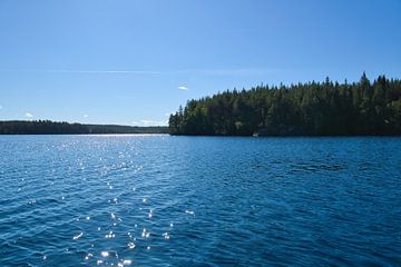 Lake in Sweden with white clouds, blue water and trees on the shore by Martin Köbsch