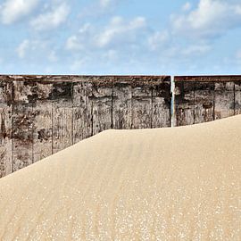 Zandverstuiving tegen een houten muur op het strand van Hans Kwaspen