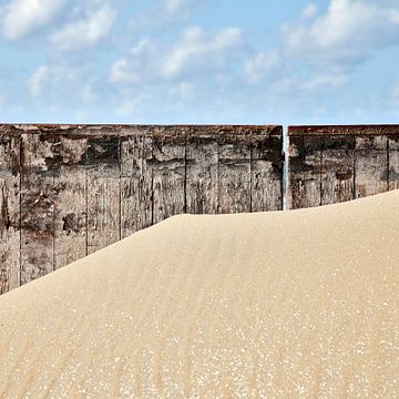 Zandverstuiving tegen een houten muur op het strand van Hans Kwaspen