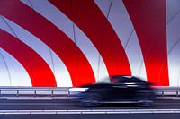 Een zwarte auto die snel rijdt door een tunnel met rode dynamische strepen