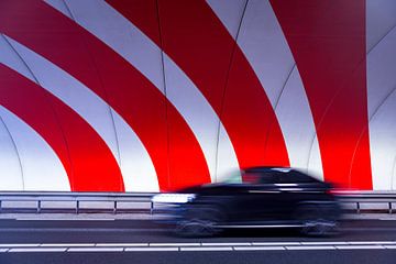 A black car driving fast in a tunnel with red dynamic stripes by Pixable