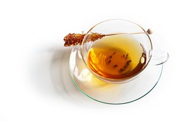 Tasse en verre à moitié remplie de thé noir et d'un bâton de sucre candi avec une ombre réfléchissan sur Maren Winter