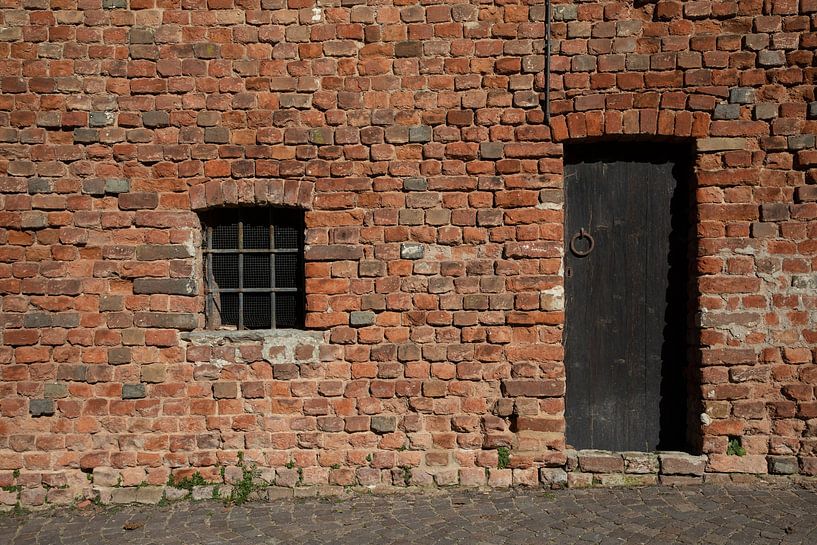 Detail bakstenen muur met deur in Cortanze, Piemonte, Italië van Joost Adriaanse
