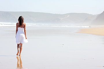 Jonge vrouw wandelt langs een verlaten strand van Eye on You