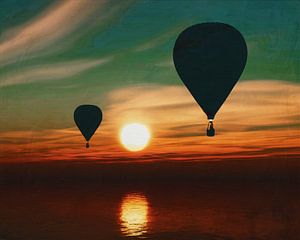 Hot air balloons sail over the sea during sunset