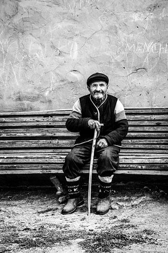 Freundlicher alter Mann auf einer Bank in Schwarz und Weiß