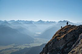 Climbers on the summit of the Aggenstein with a view of the Tannheimer Valley and the Allgäu Alps, including the Hochvogel