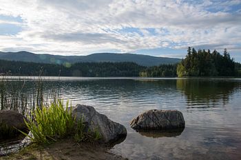 Ruhiger See mit klarem Wasser und Bergen im Hintergrund