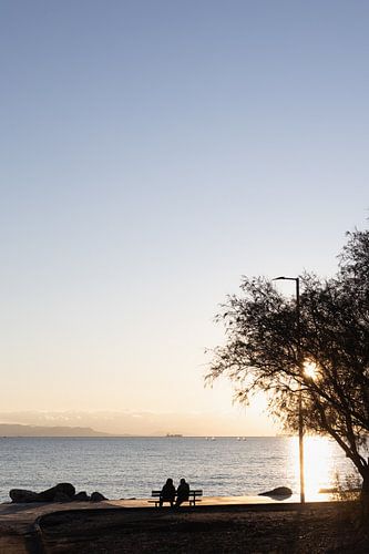 Couple at sunset by the sea in Greece by Jochem Oomen