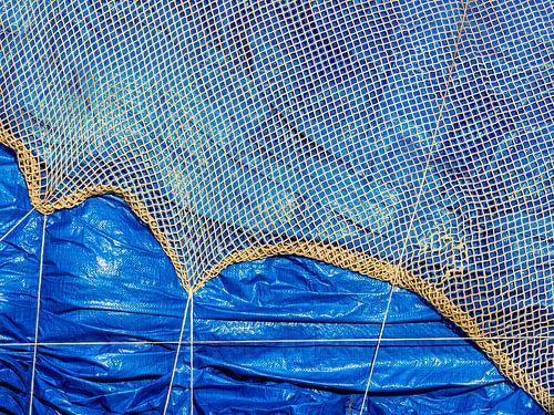 Een visnet dat over een blauw zeil hangt in Sciacca