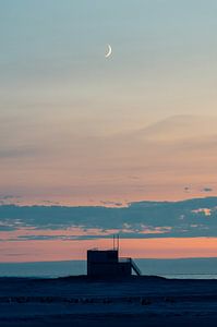 Lune croissante au-dessus d'une tour de sauvetage et de la mer du Nord. sur Alex Hamstra