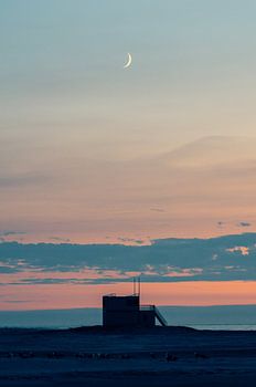 Wassende Maan boven een strandwachterstoren en de Noordzee