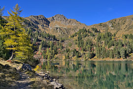Bergmeer in de herfst met weerspiegeling van bomen en bergen van Tomherkules