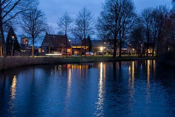 Na zonsondergang, de lucht is blauw, het water donker blauw, lichten trekken verticale strepen van Jan Willem de Groot Photography