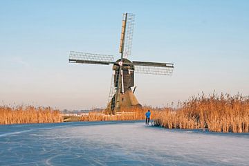Schaatsen op het platteland op een koude winterdag in Nederland bij een traditionele molen van Eye on You