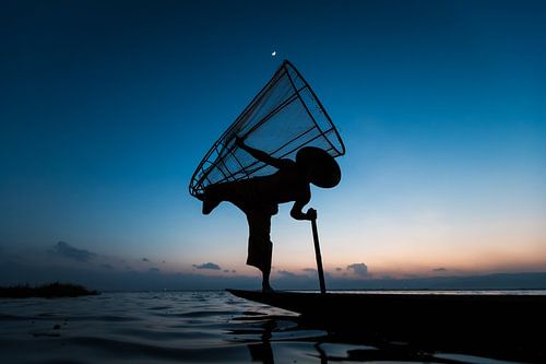 FISHERMAN AT SUNRISE vist ON TRADITIONAL WAY TO INLE LAKE IN MYANMAR. With a basket the fish is caug