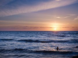 Surfers in the sea during sunset. by Sjoerd van der Hucht