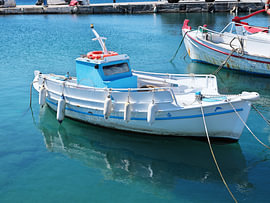Un bateau de pêche grec traditionnel est ancré dans les eaux turquoise sur Tomherkules