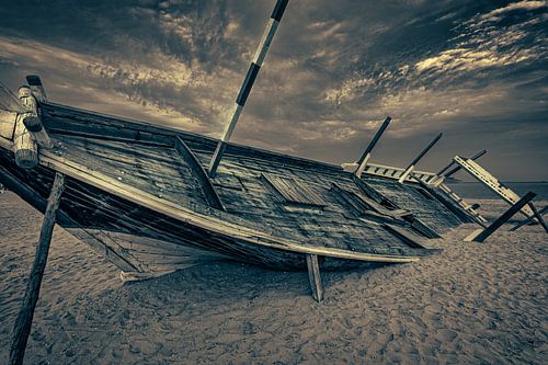 Oude Arabische houten boot (dhow) die op het strand is gestrand zwart-wit close-up beeld