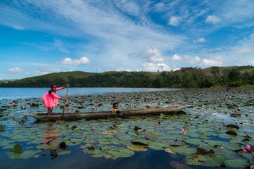 Young girl takes her little brother away by traditional canoe by Anges van der Logt