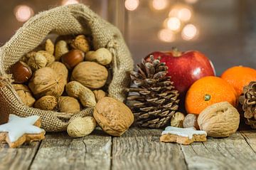 Christmas food with nuts in santa claus bag, red apple, orange fruit and star shape cookie by Alex Winter