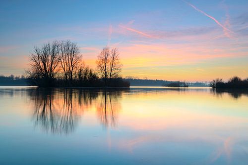 Zonsondergang over een meer met kleine eilandjes aan het eind van een winterdag