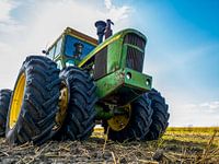 Grüner John Deere Traktor auf einem bewirtschafteten Acker