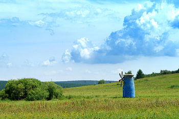 Blauwe windmolen onder torenhoge wolken